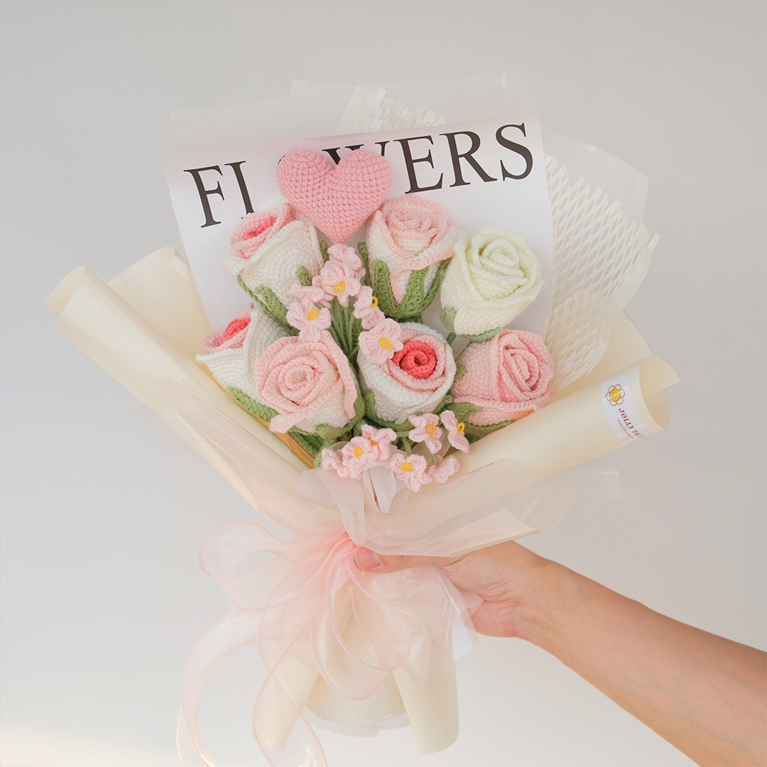 A bouquet of crocheted pink roses and white baby's breath flowers, with a label that reads 'FLOWERS'.