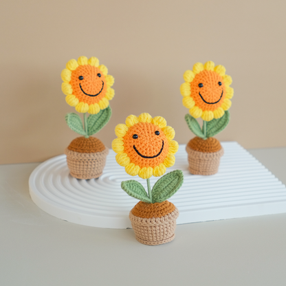 Handmade crochet sunflowers in pots, displayed on a white surface, with a beige background.